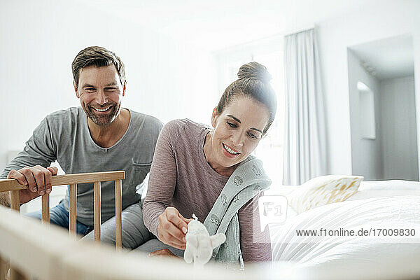 Lächelnd reifen Mann und Frau mit ausgestopften Elefanten Spielzeug spielen von Krippe im Schlafzimmer