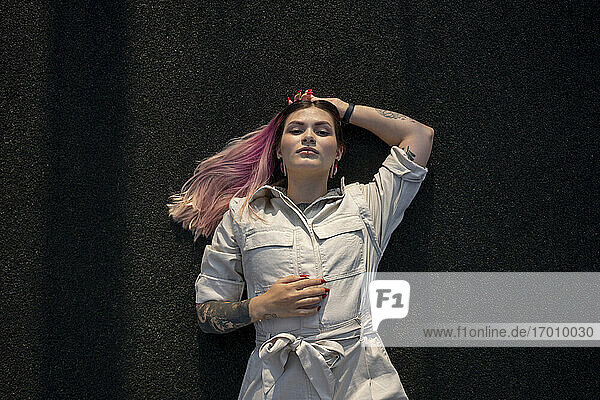 Fashionable woman with pink hair lying on sports court
