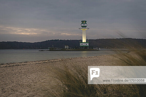 Deutschland  Schleswig-Holstein  Friedrichsort  Sandstrand in der Morgendämmerung mit Leuchtturm im Hintergrund
