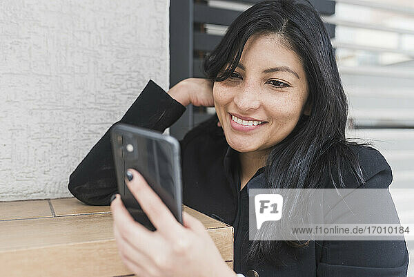 Schöne Frau nimmt Selfie auf Handy  während lehnt an der Wand
