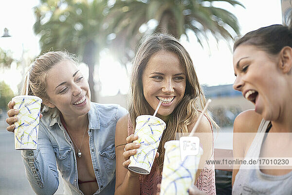 Unbekümmerte Freunde trinken im Urlaub am Strand gekühlte Getränke