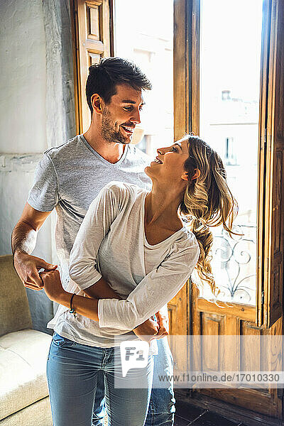 Verliebtes junges Paar tanzt zu Hause am Fenster