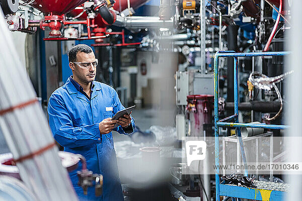 Male technician using digital tablet while working in factory