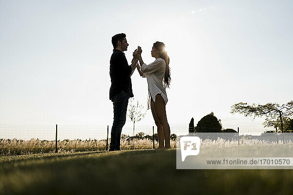Affectionate dancing couple in field on sunny day