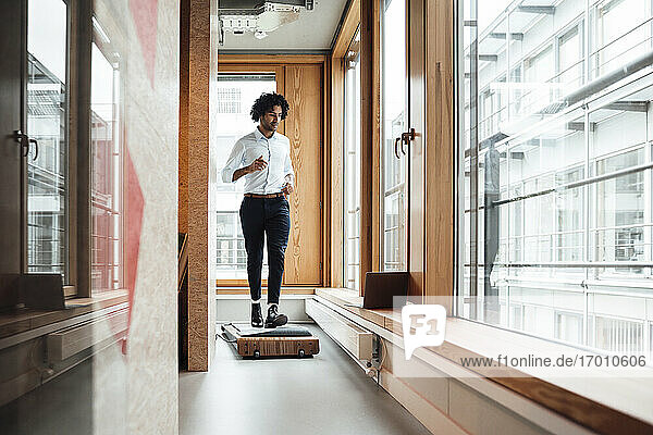 Aktiver junger Geschäftsmann joggt auf einem Laufband vor einem Fenster am Arbeitsplatz