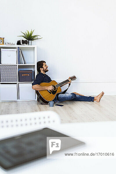 Musiker spielt Gitarre  während er im Studio auf dem Boden sitzt