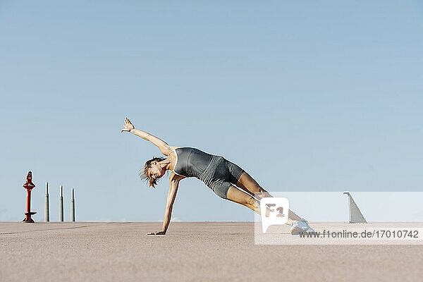 Weibliche Sportlerin übt Yoga und balanciert auf einer Seite