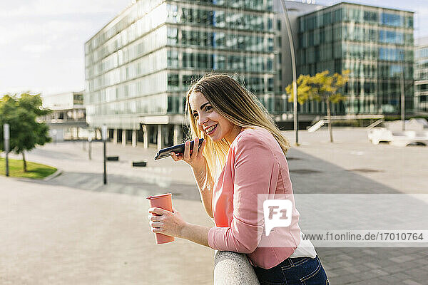 Spanien  Barcelona  Lächelnde Frau beim Telefonieren in der Stadt