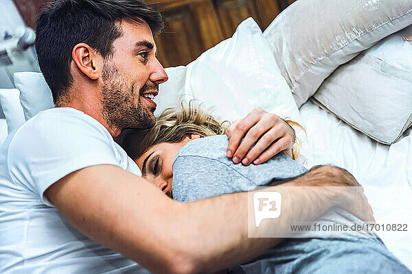 Happy affectionate young couple cuddling in bed at home