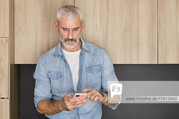 Handsome mature man using smart phone at home