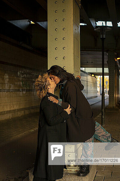 Lesbisches Paar  das sich nachts unter einer Brücke küsst