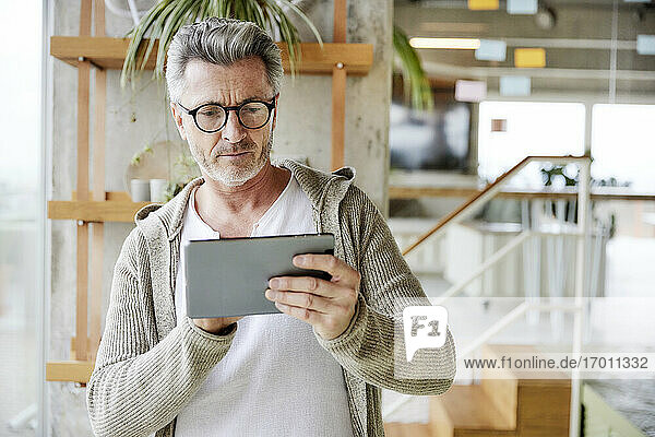 Älterer Mann mit Brille und digitalem Tablet