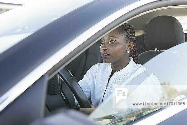 Junge Frau beim Autofahren durch das Fenster gesehen