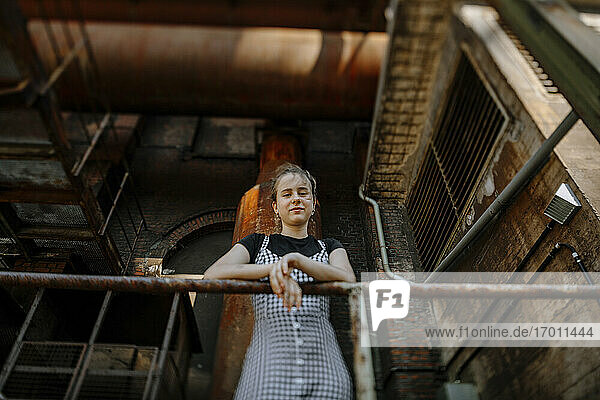 Teenager-Mädchen steht am Geländer eines verlassenen Gebäudes