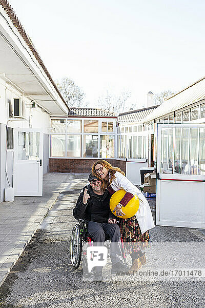 Weibliche Pflegekraft umarmt behinderten Mann vor einem Pflegeheim