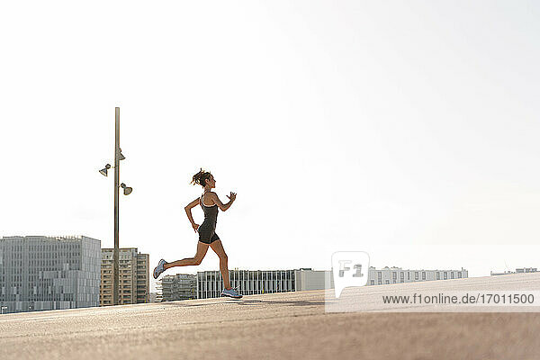 Weibliche Sportlerin beim Joggen an einem sonnigen Tag in der Stadt