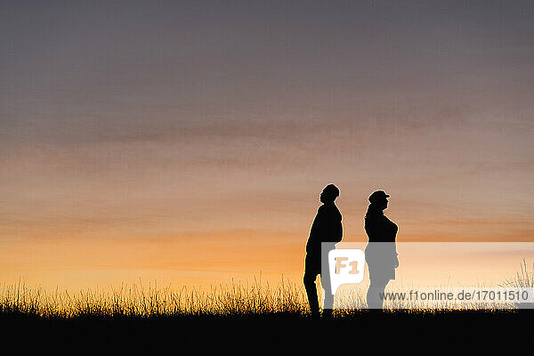In silhouette of man and woman standing against sky