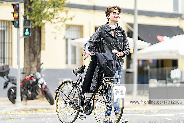 Glücklicher junger Mann mit Fahrrad auf der Straße in der Stadt