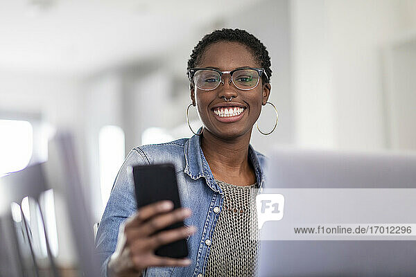 Smiling woman working using laptop and smart phone at home