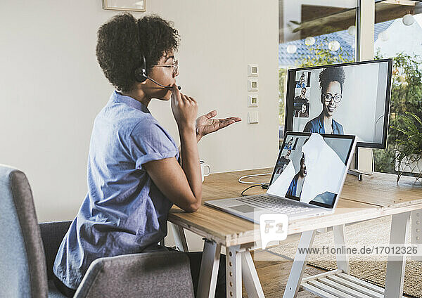 Frau hält Videokonferenz mit Kollegen über Laptop zu Hause