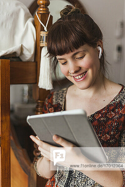 Schöne Frau liest Nachrichten auf einem digitalen Tablet  während sie zu Hause über Kopfhörer Musik hört