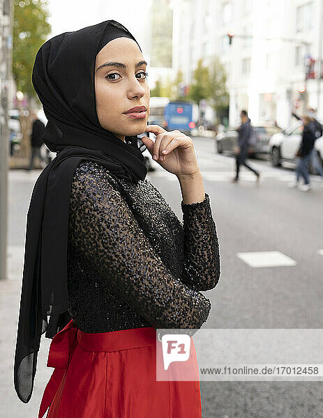 Portrait of young beautiful woman wearing black hijab posing on city street