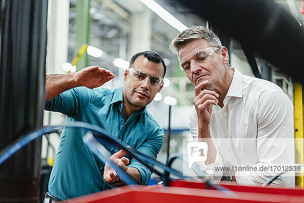 Männliche Kollegen mit Brillen  die Produktionsanlagen in der Industrie untersuchen