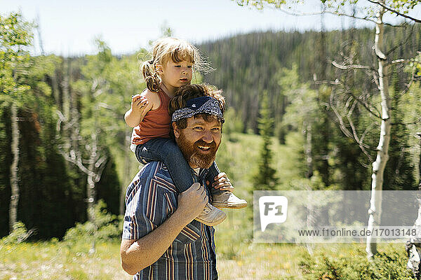 USA  Utah  Uinta National Park  Porträt eines lächelnden Mannes  der seine Tochter (2-3) auf den Schultern trägt  in einer Landschaft