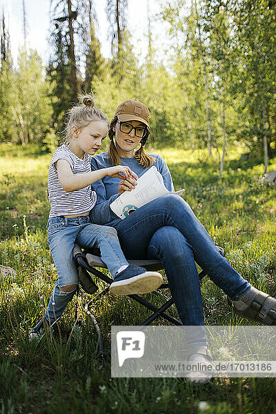 USA  Utah  Uinta National Park  Mutter und Tochter (6-7) machen Kreuzworträtsel auf einer Wiese im Wald