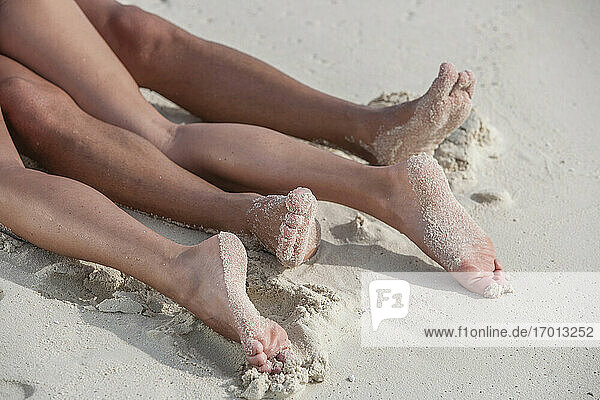 Legs of couple lying on beach