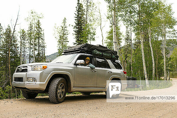 USA  Utah  Uinta National Park  Woman sitting in off road car with tent on roof