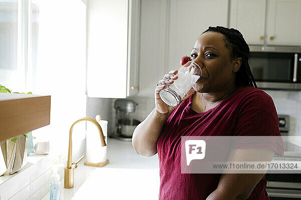 Frau trinkt Wasser in der Küche