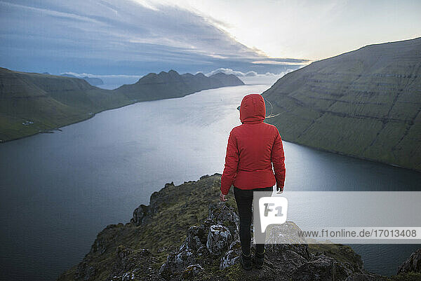 Dänemark  Färöer Inseln  Klaksvik  Frau steht auf dem Gipfel des Berges Klakkur über dem Meer und schaut auf die Aussicht