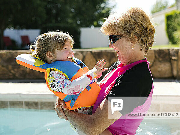 Großmutter hält Kleinkind Mädchen (2-3) auf Freibad