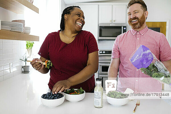 Glücklicher Mann und Frau bereiten Salat in der Küche