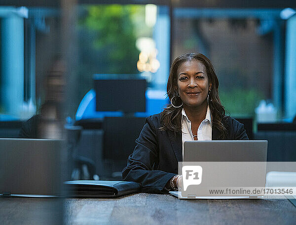 Porträt der lächelnden Geschäftsfrau sitzt am Schreibtisch mit Laptop im Büro