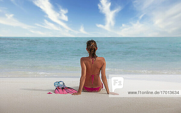 Malediven  Rückansicht einer Frau im Bikini  die am Strand sitzt