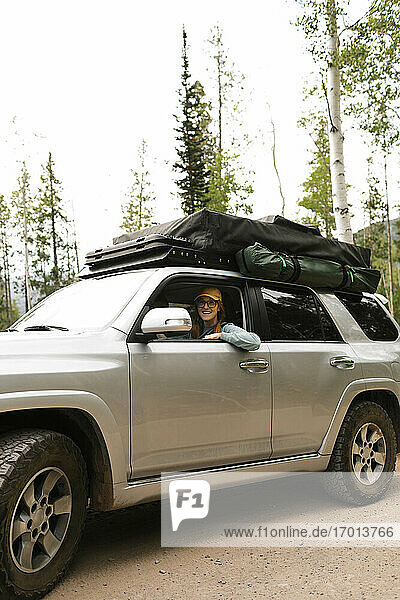 Frau sitzt im Geländewagen mit Zelt auf dem Dach