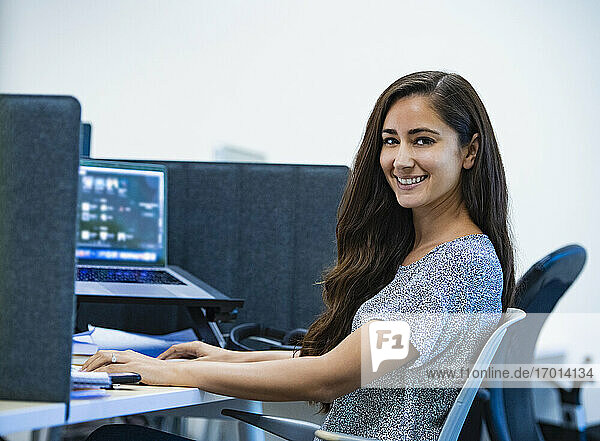 Porträt der lächelnden Frau sitzt am Schreibtisch im Büro