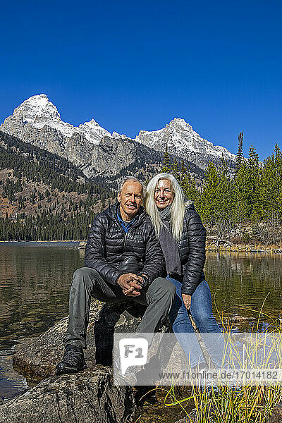 USA  Wyoming  Jackson  Grand Teton National Park  Outdoor-Portrait eines älteren Paares  das auf einem Felsen am Taggart Lake im Grand Teton National Park sitzt