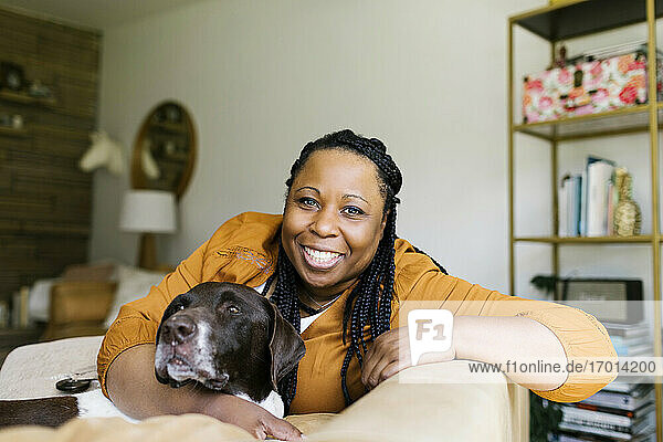 Portrait of smiling woman sitting on sofa with dog