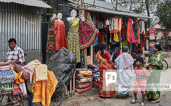 Indien  Westbengalen  Mayapur. Die Hauptstraße  die vom Ufer in die Stadt führt  ist gesäumt von Geschäften  die Kleidung  Taschen und Kinderspiele verkaufen...