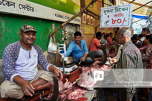 Chandannagar  West Bengal  India. Buyers pass by a market street while chicken butchers sit in their stall harangue customer in the old town of Chandannagar