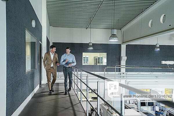 Businessman with male coworker in walkway at industry