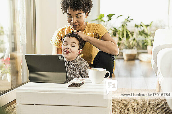 Mutter und Sohn benutzen ein digitales Tablet  während sie zu Hause sitzen