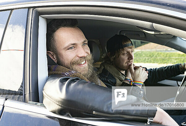 Gay boyfriends holding hands while enjoying road trip in car