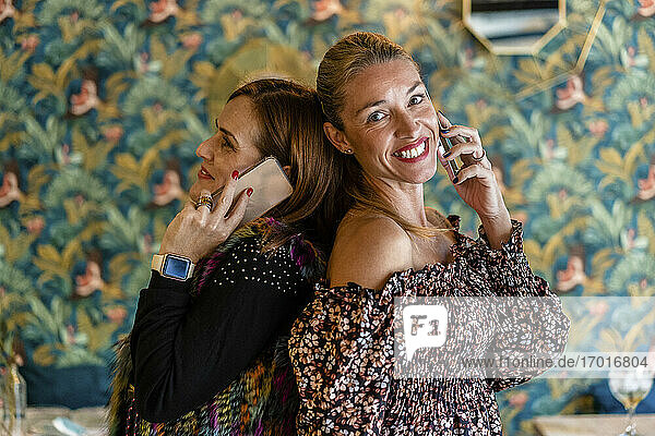 Porträt von zwei Frauen  die sich mit ihren Smartphones unterhalten