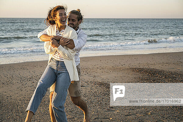 Glückliches junges Paar genießt am Strand bei Sonnenuntergang