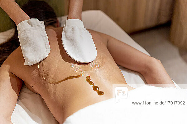 Female therapist massaging woman's back with oil at beauty spa