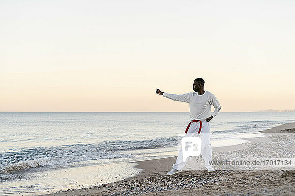Erwachsener Mann beim Üben von Kampfsportarten am sandigen Küstenstrand